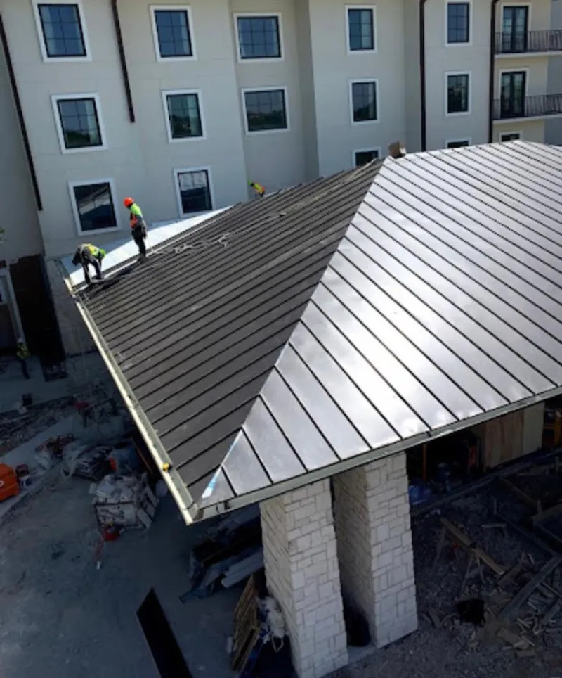 Crew installing standing seam metal roof panels on a commercial project in Marlin